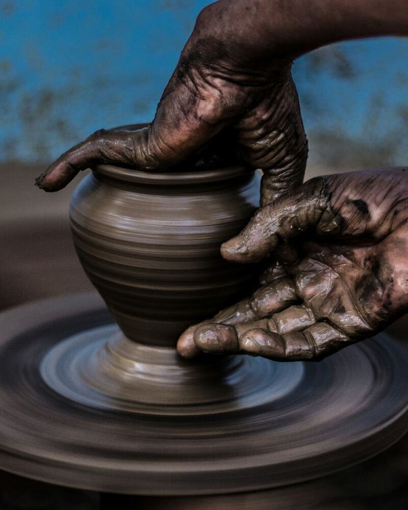 Mains d'une céramiste façonnant un pot au tour